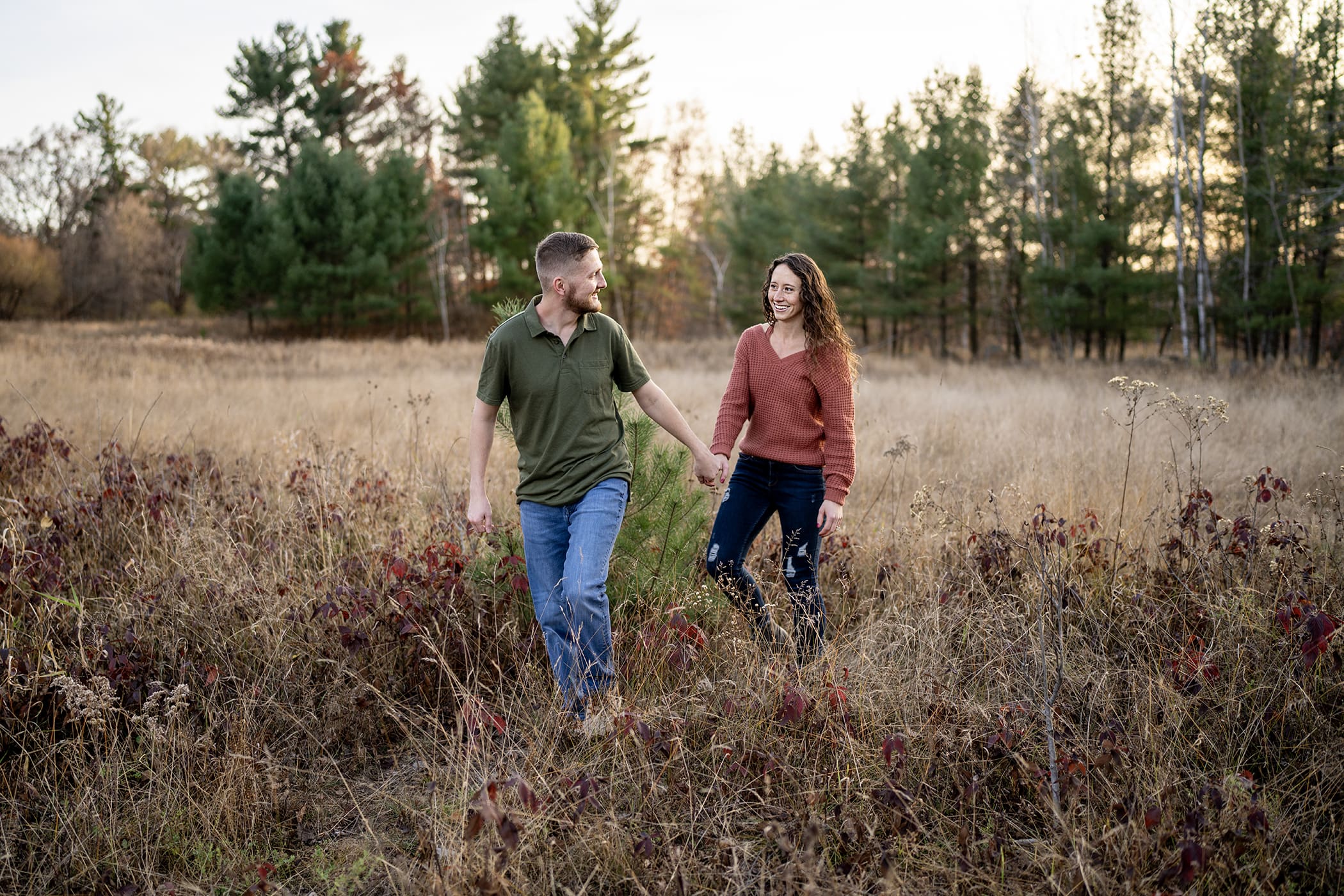 Candid shot of couple walking through a field in the fall. 