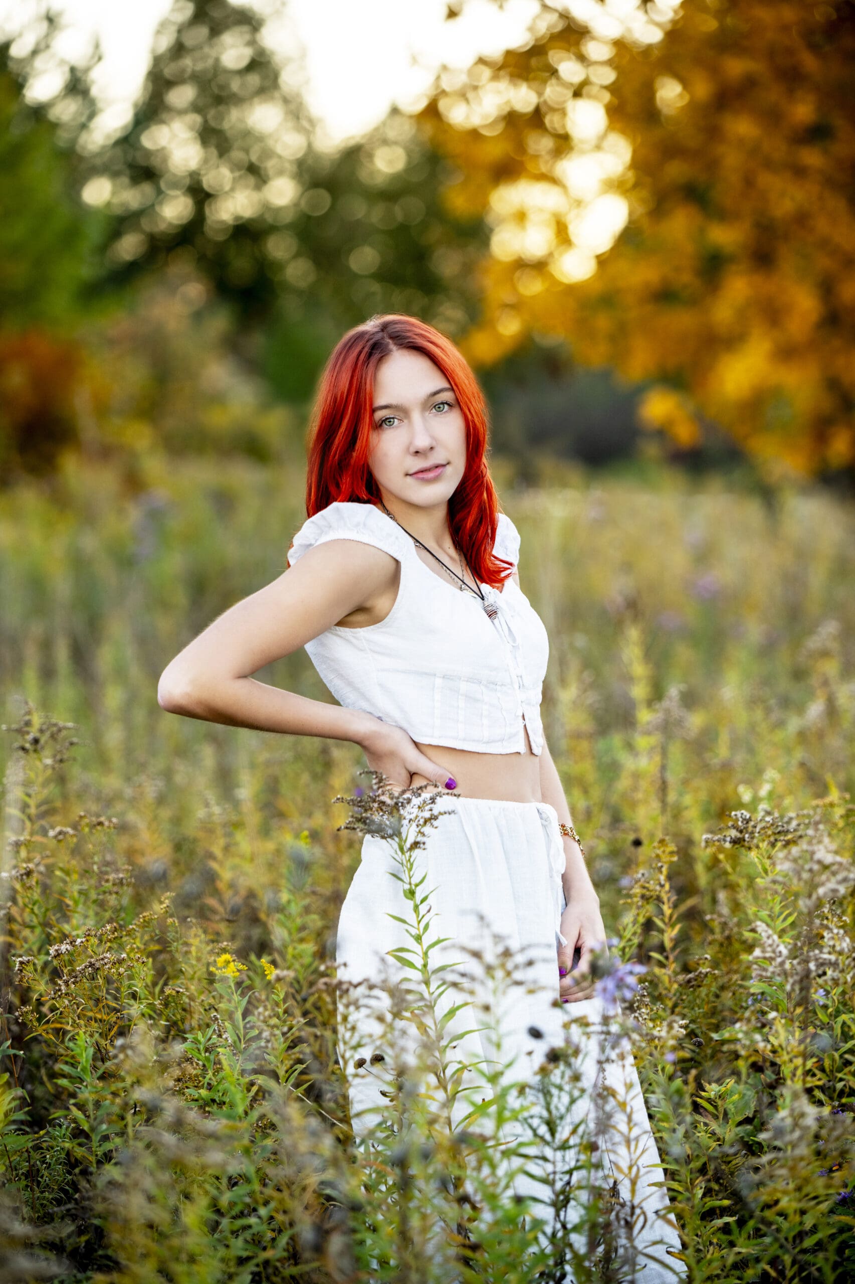 Golden Hour Senior Photos in Wisconsin; girl standing in flower field with her hand on her hip.