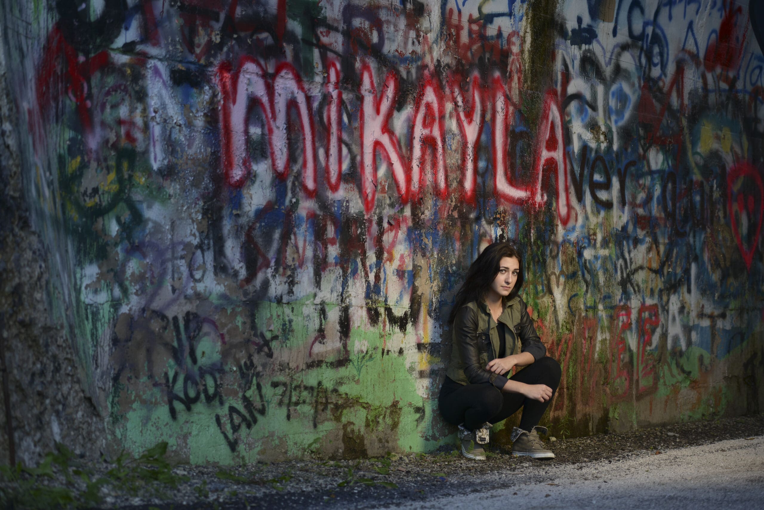 Hartland senior girl leaning against graffiti wall near Merton studio. 