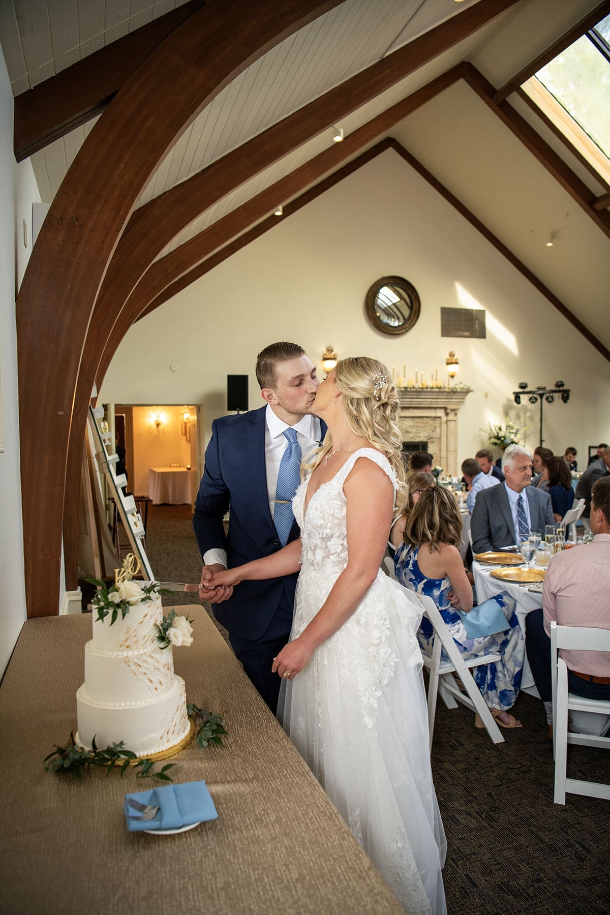 Groom and bride kissing before cutting the wedding cake 