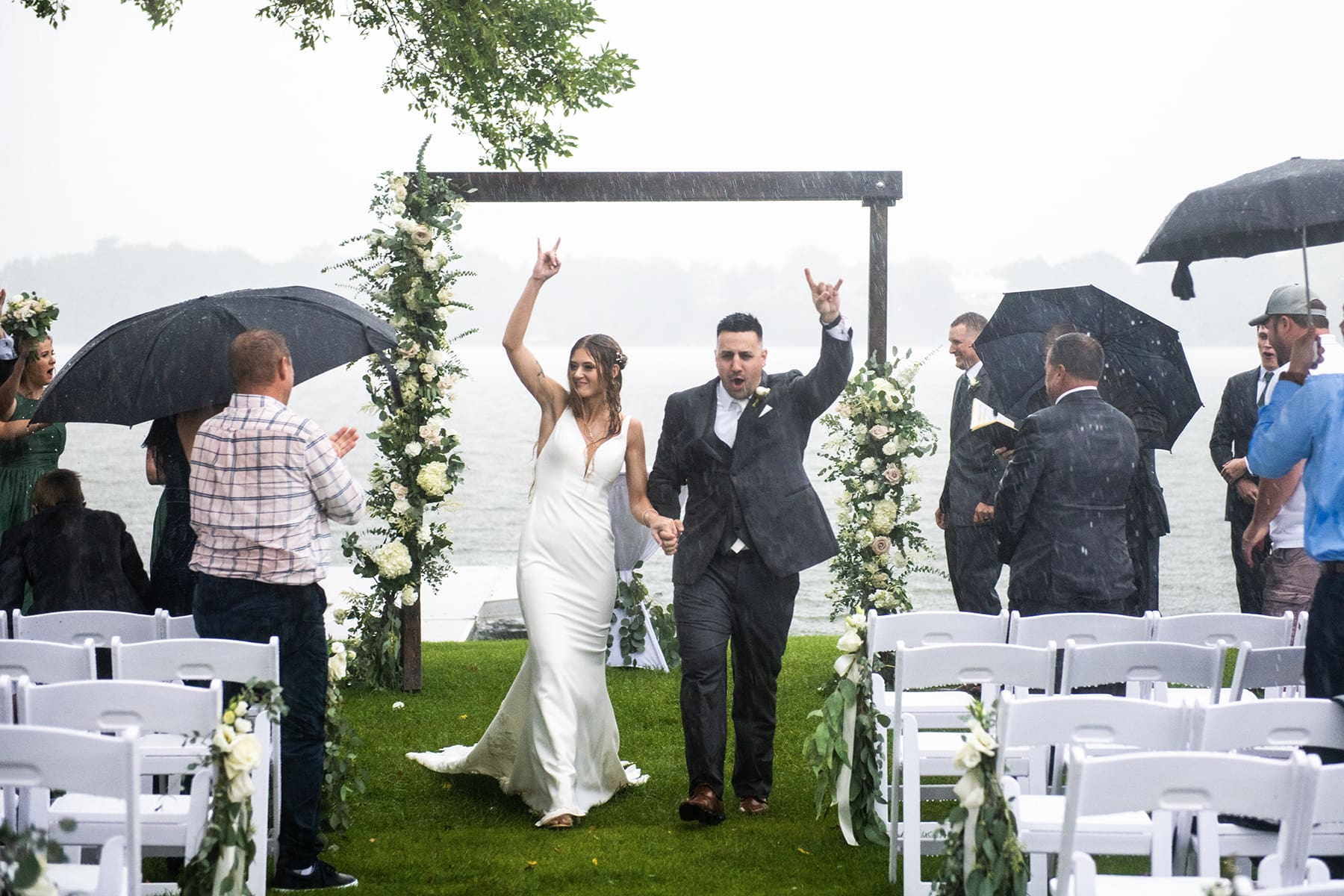 Bride and groom descending Wisconsin ceremony aisle in the rain