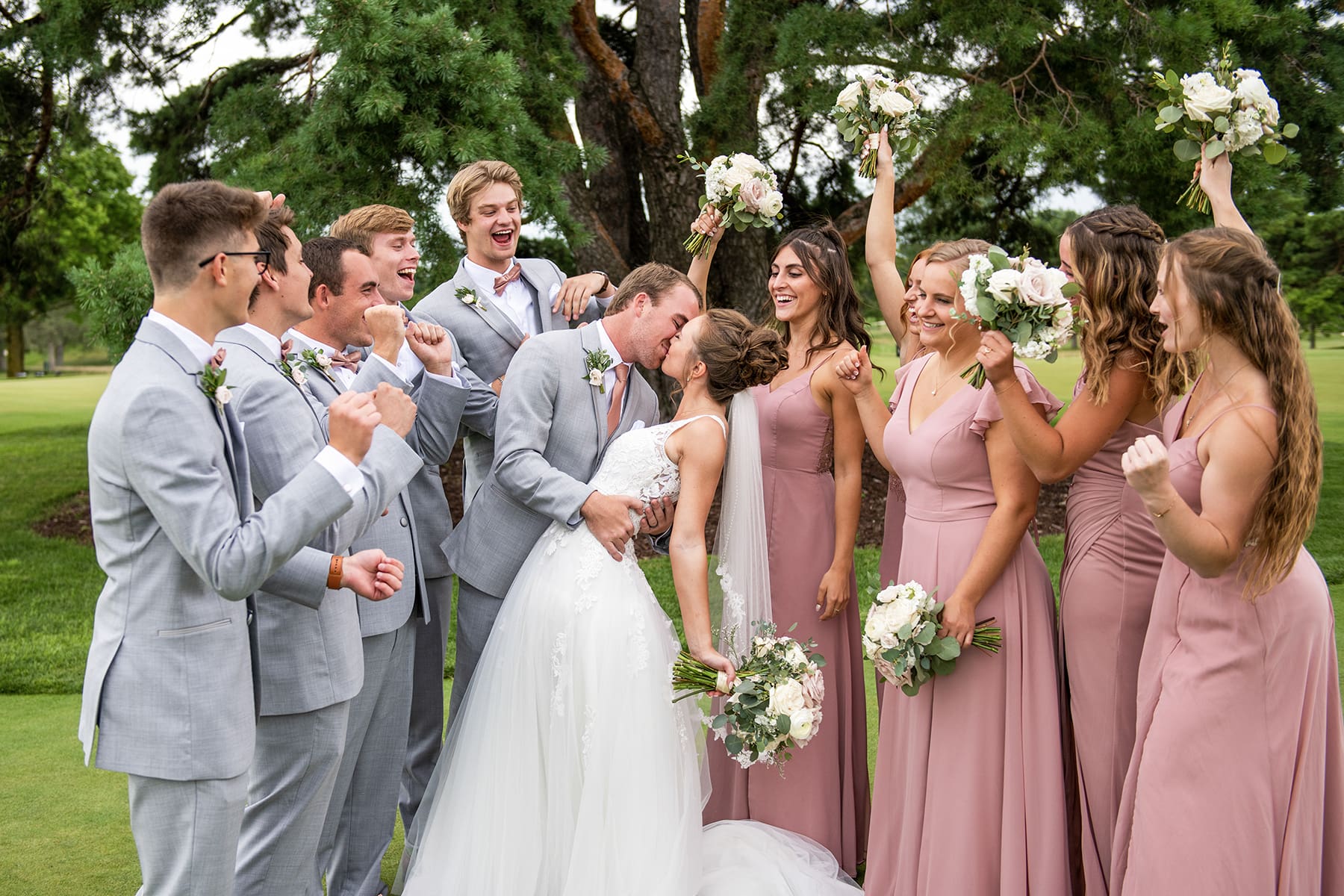 Oconomowoc groom and bride kissing as wedding party cheers