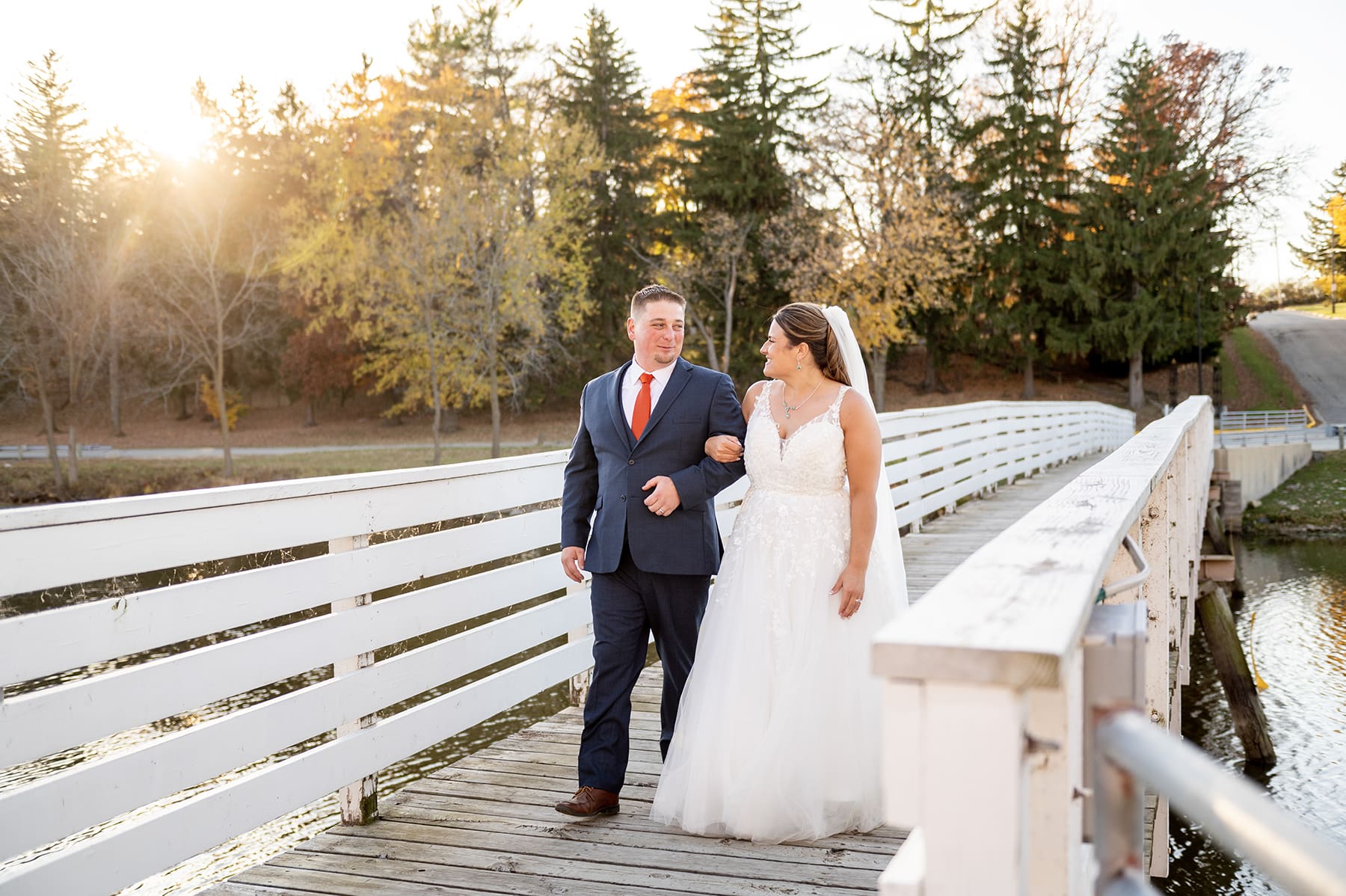 Groom and bride walking on bridge during golden hour in Southeast WI.