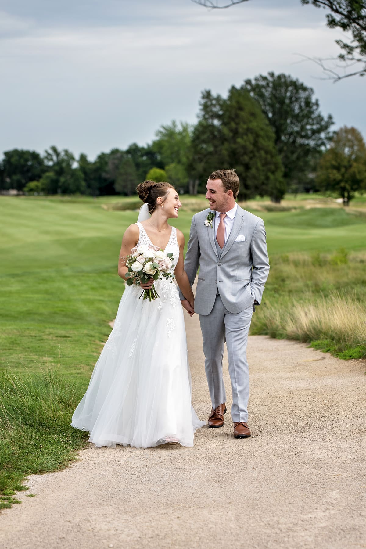 Bride and groom walking on golf course path at Lac La Belle