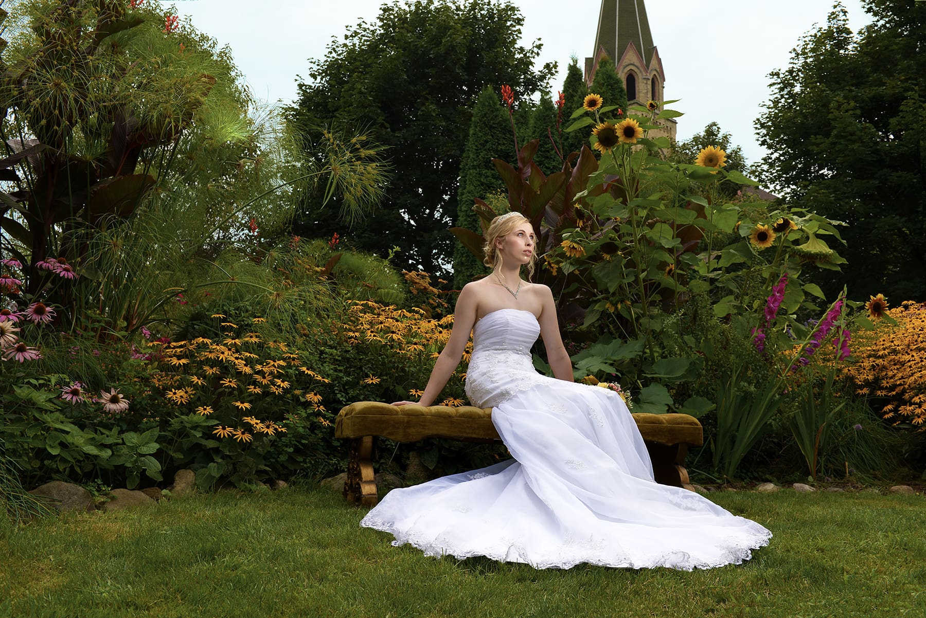 Milwaukee bride sitting on bench surrounded by flowers at The Gardens Wedding Center
