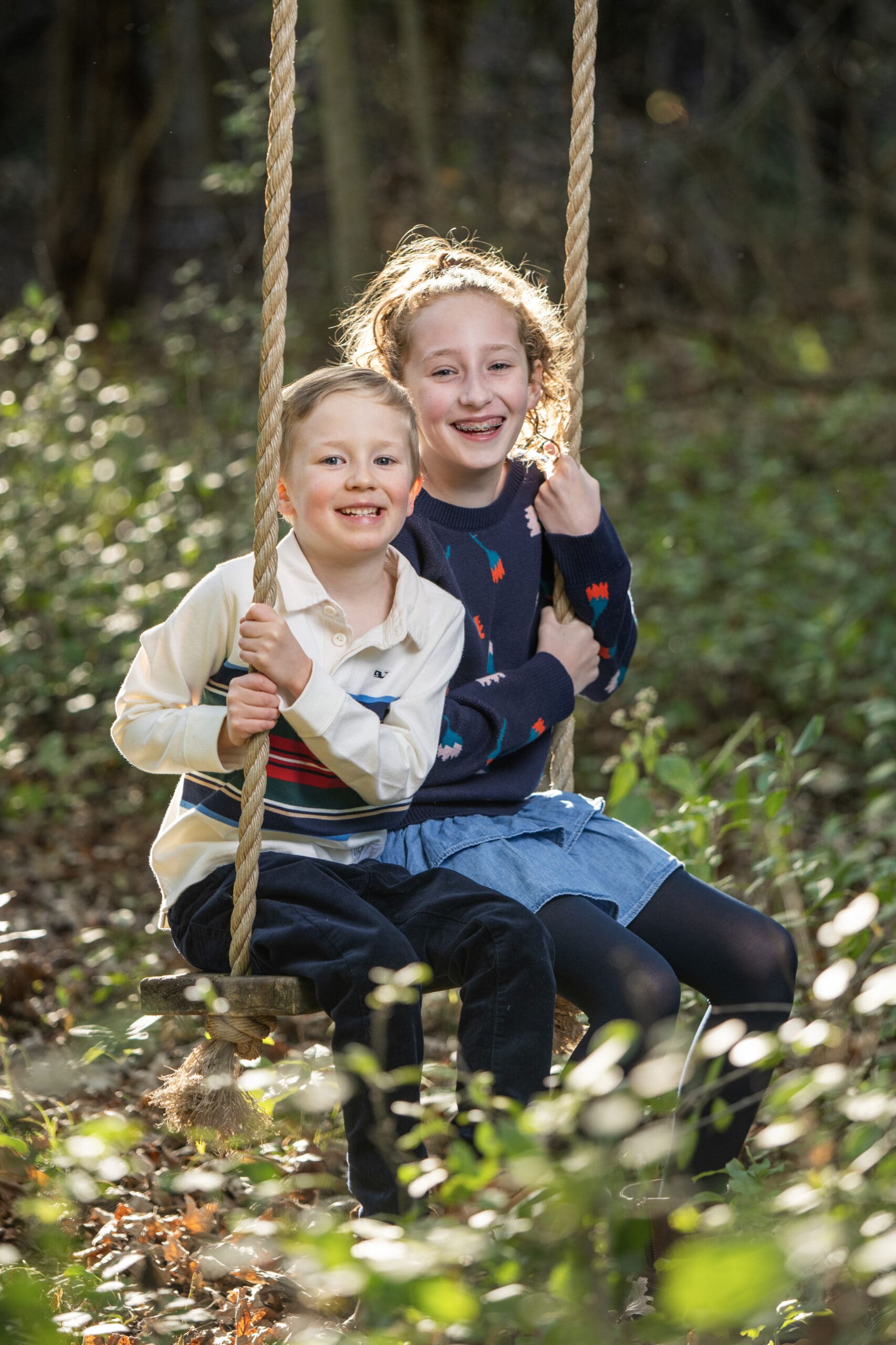 Brookfield siblings sitting on swing laughing during family photos