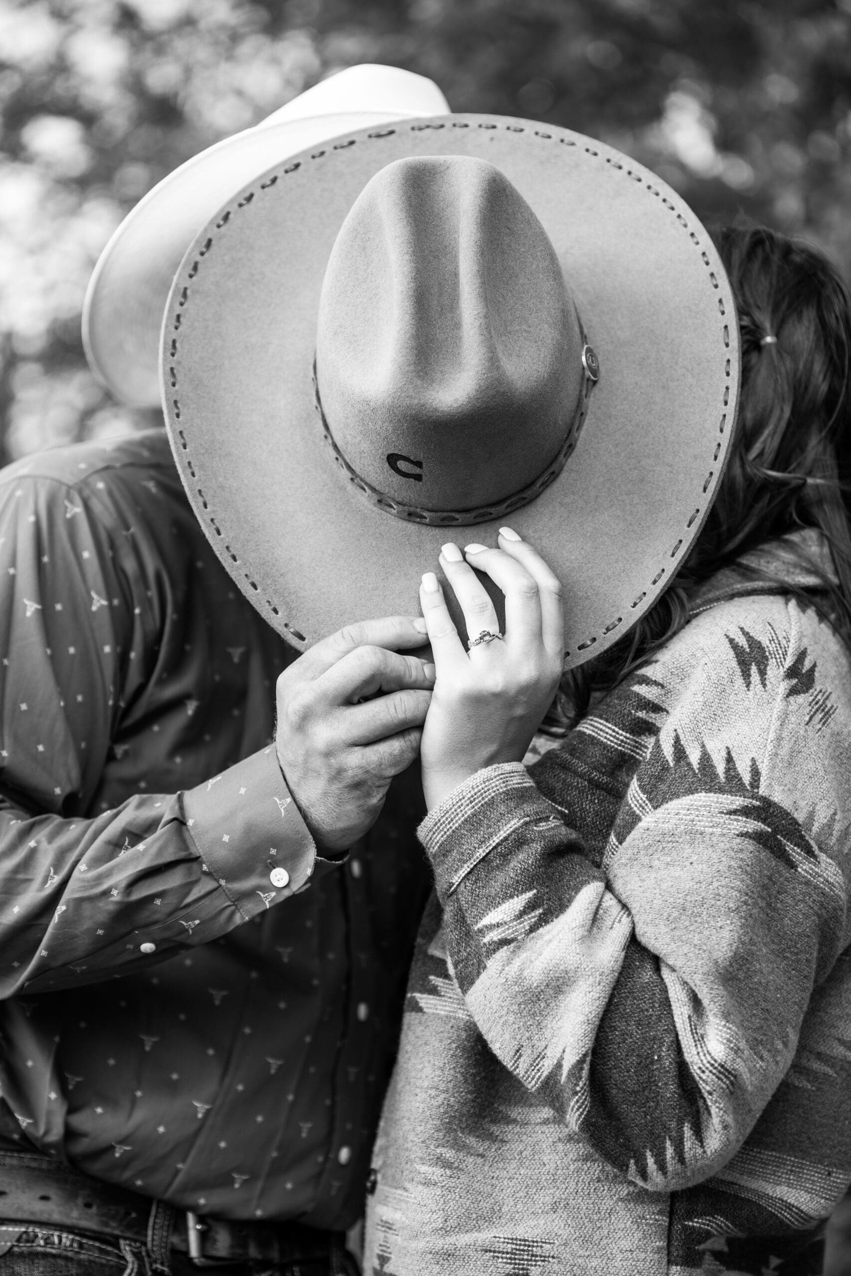 Couple holding western hat as they kiss in Delafield
