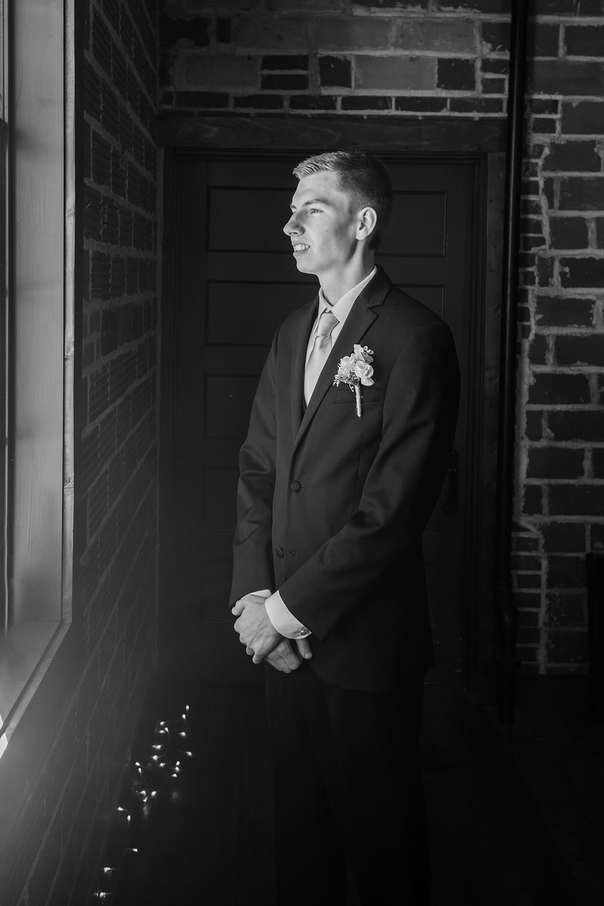 Delafield groom looking out window before wedding ceremony