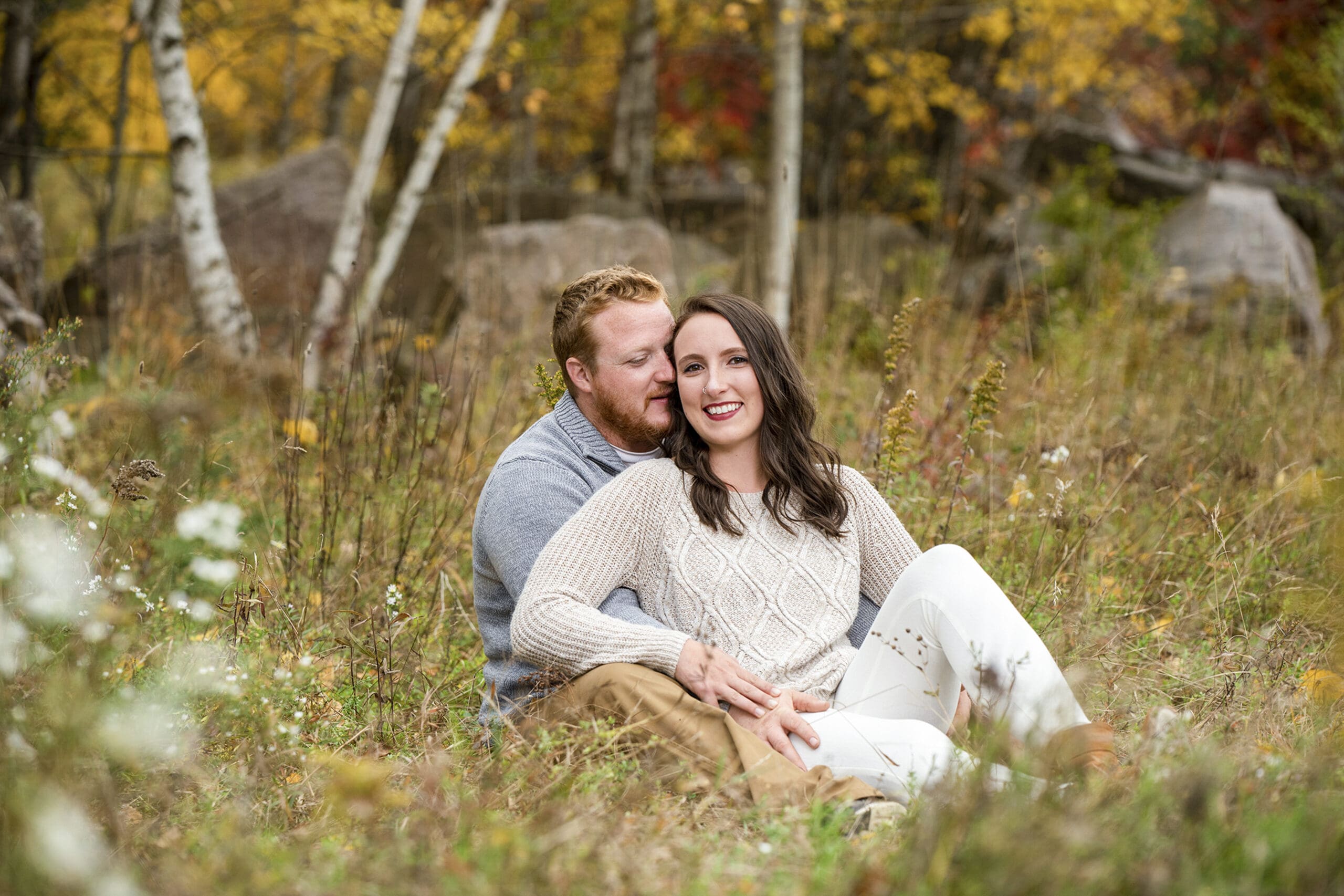 Engaged couple sitting in the field during their fall session in Lake Geneva 