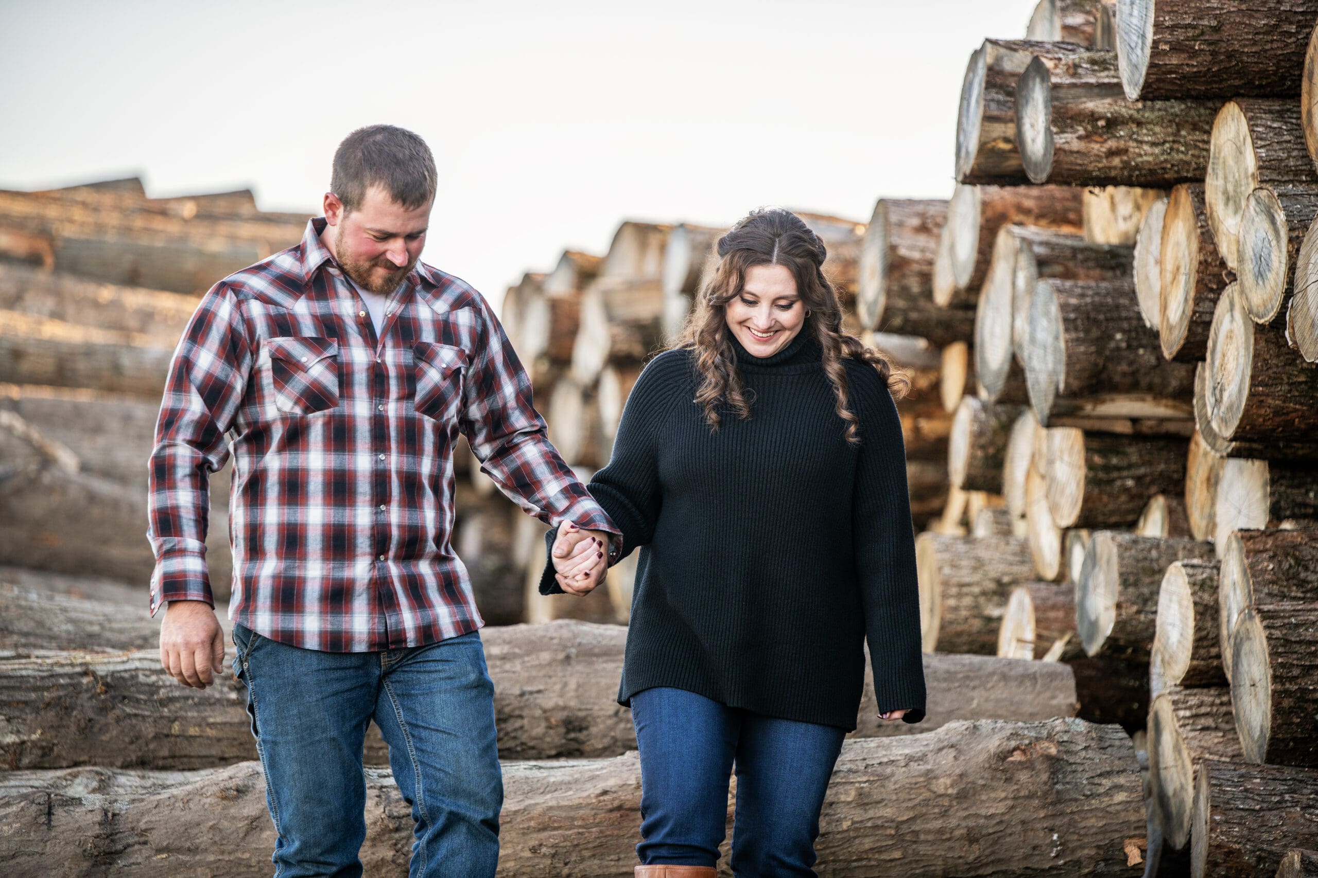 Wisconsin engaged couple walking down logs for their engagement session