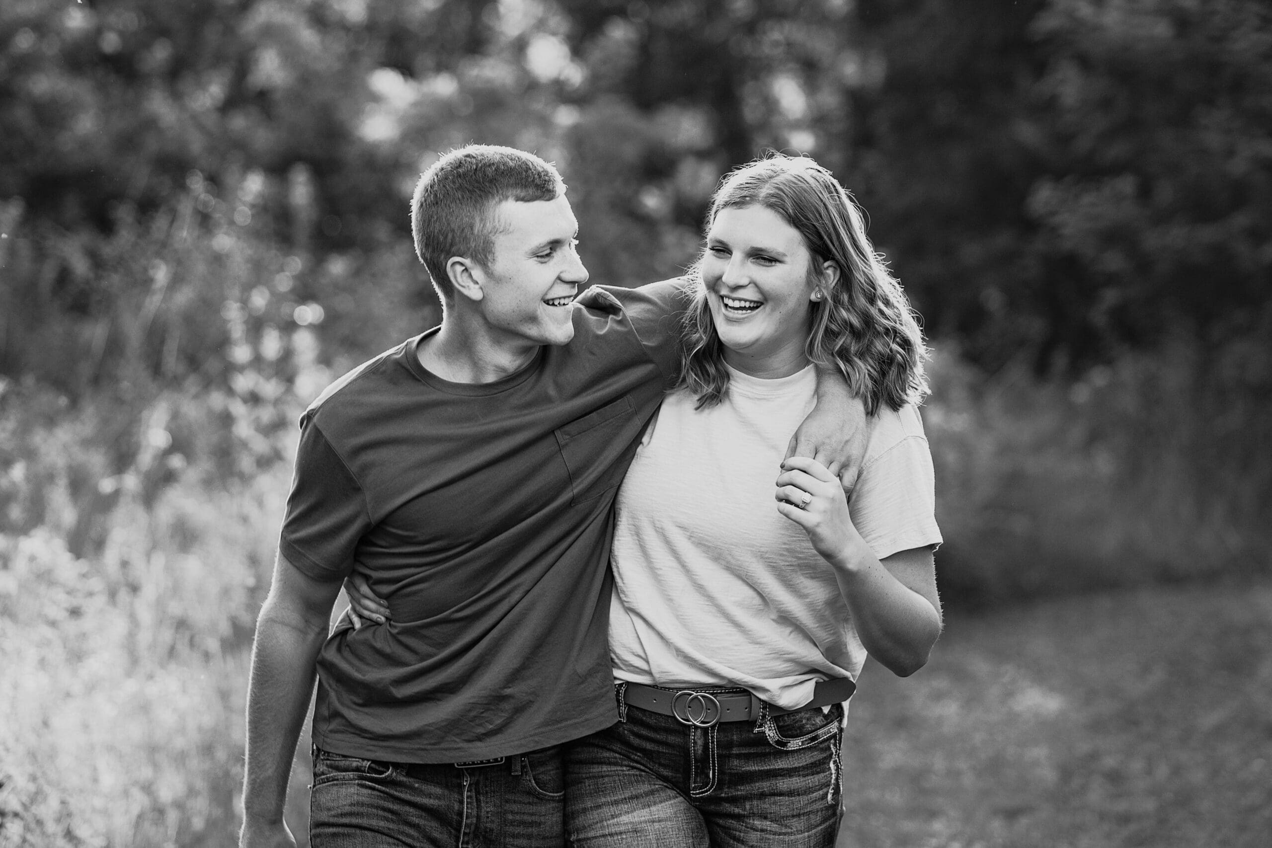 Engaged couple walking and laughing through field in Waukesha.