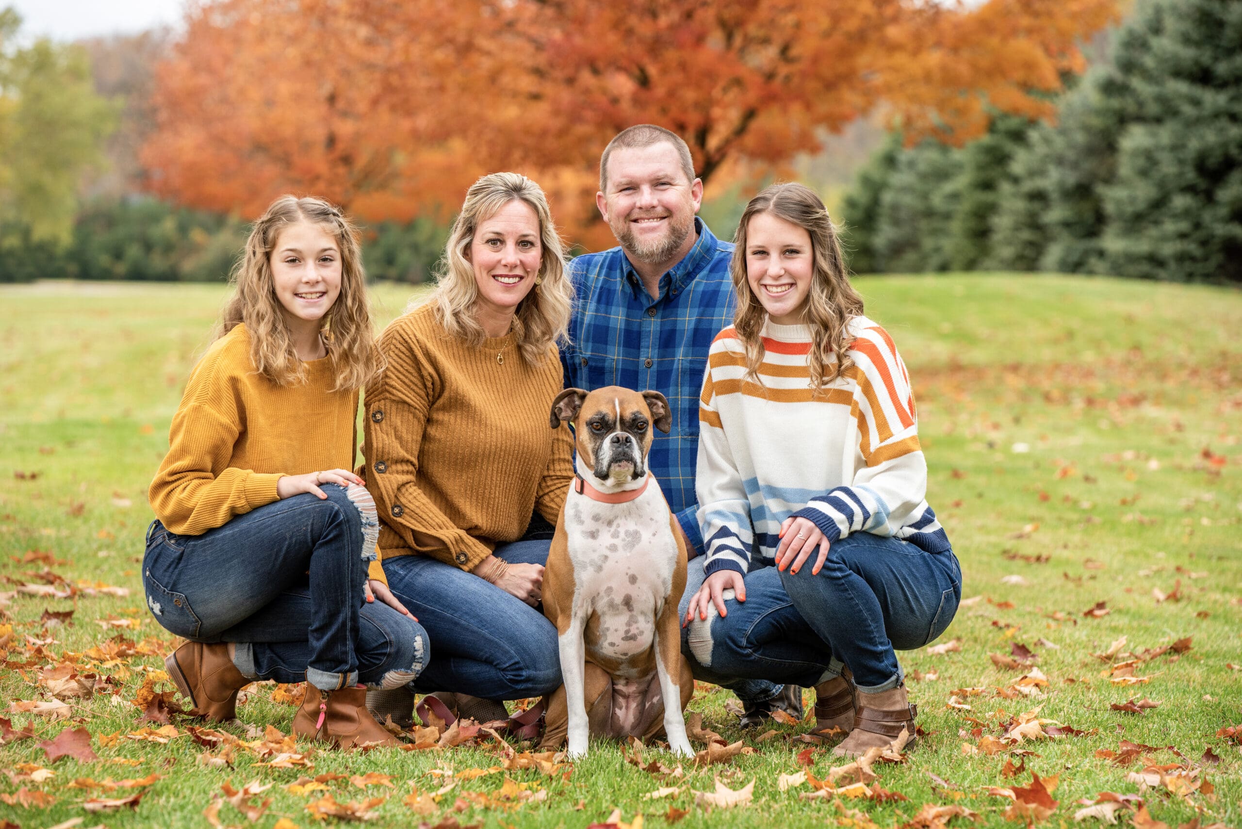 family crouching with their dog during their family photos in Oconomowoc