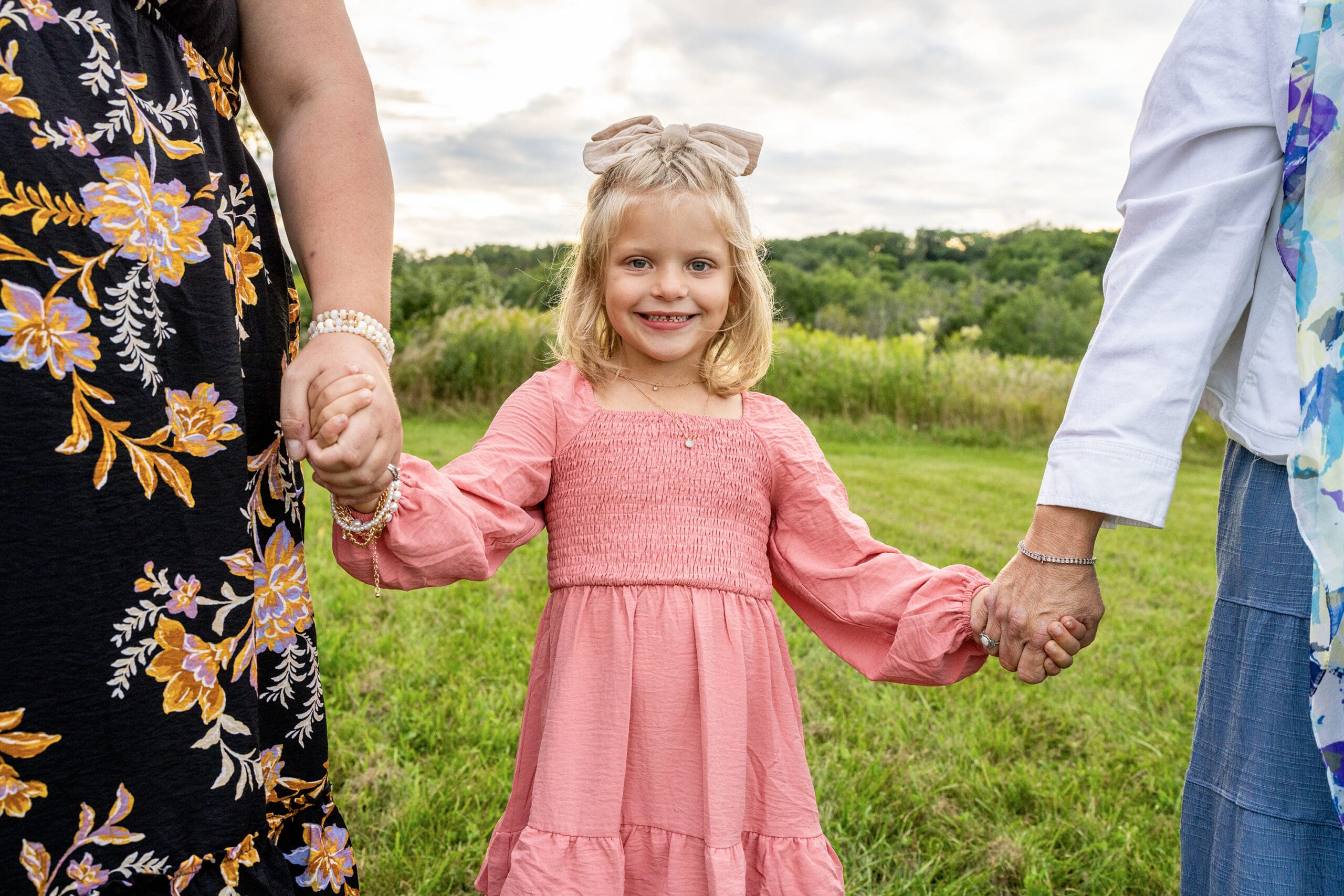 Girl holding parents hands during photo session in Waukesha