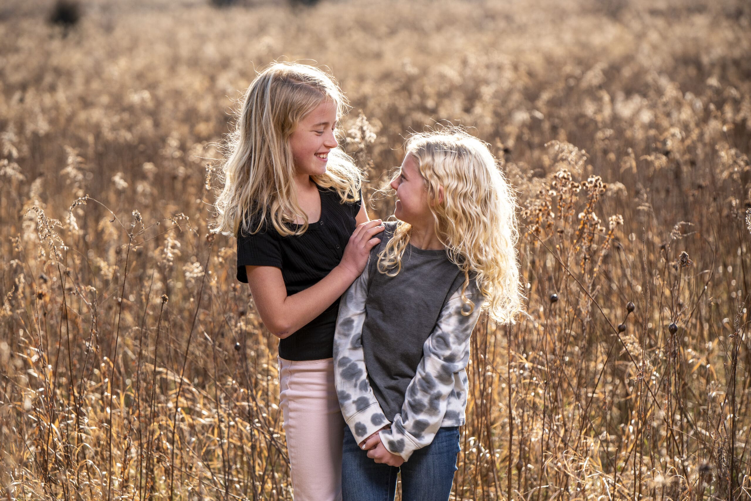 Candid family moment with siblings laughing in Hartland field. 