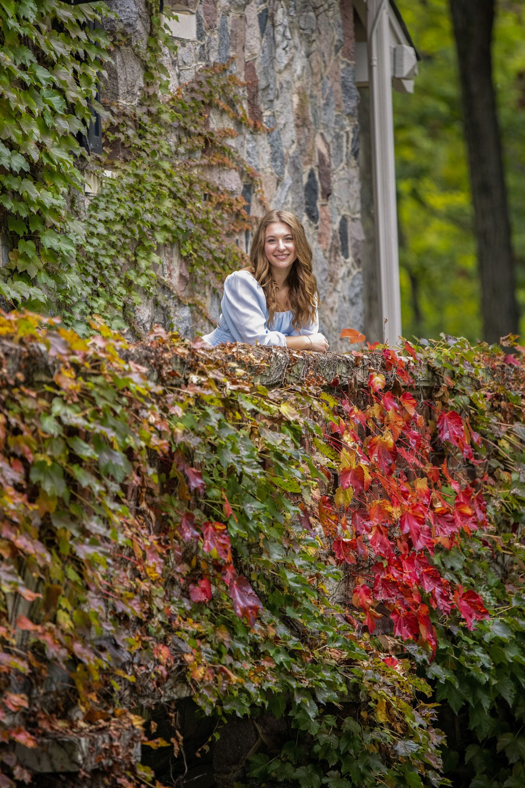 Hartland senior leaning against vine-covered wall.