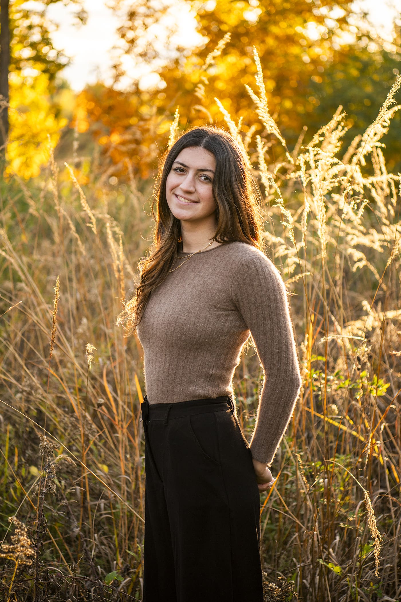 Hartland high school senior girl posing in a field during fall at golden hour — best time to take senior pictures