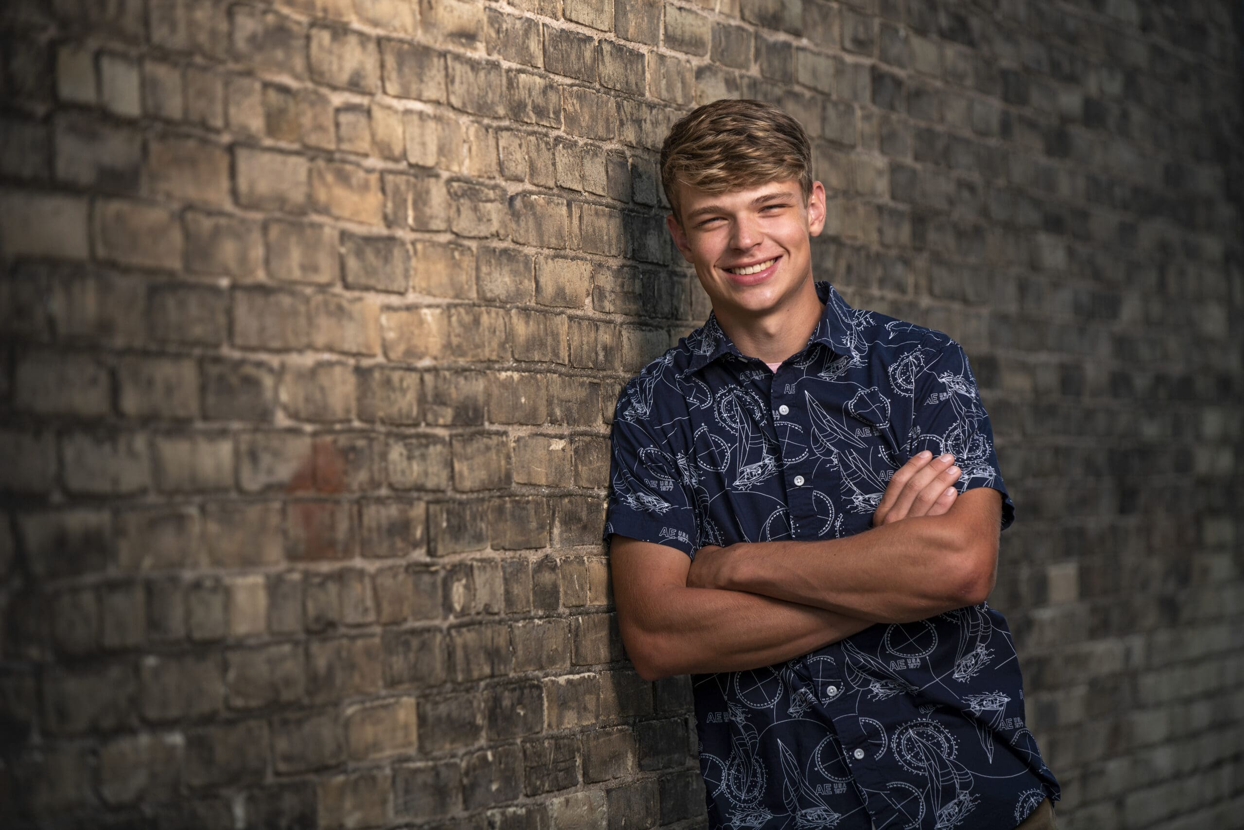 Hartland senior guy leaning against wall in town - a great location for senior portraits. 
