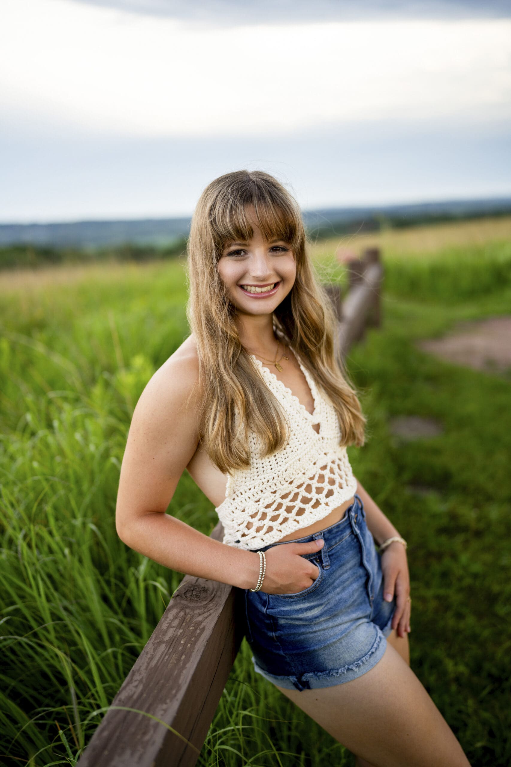 Kettle Moraine senior leaning against wooden fence at Retzer. 