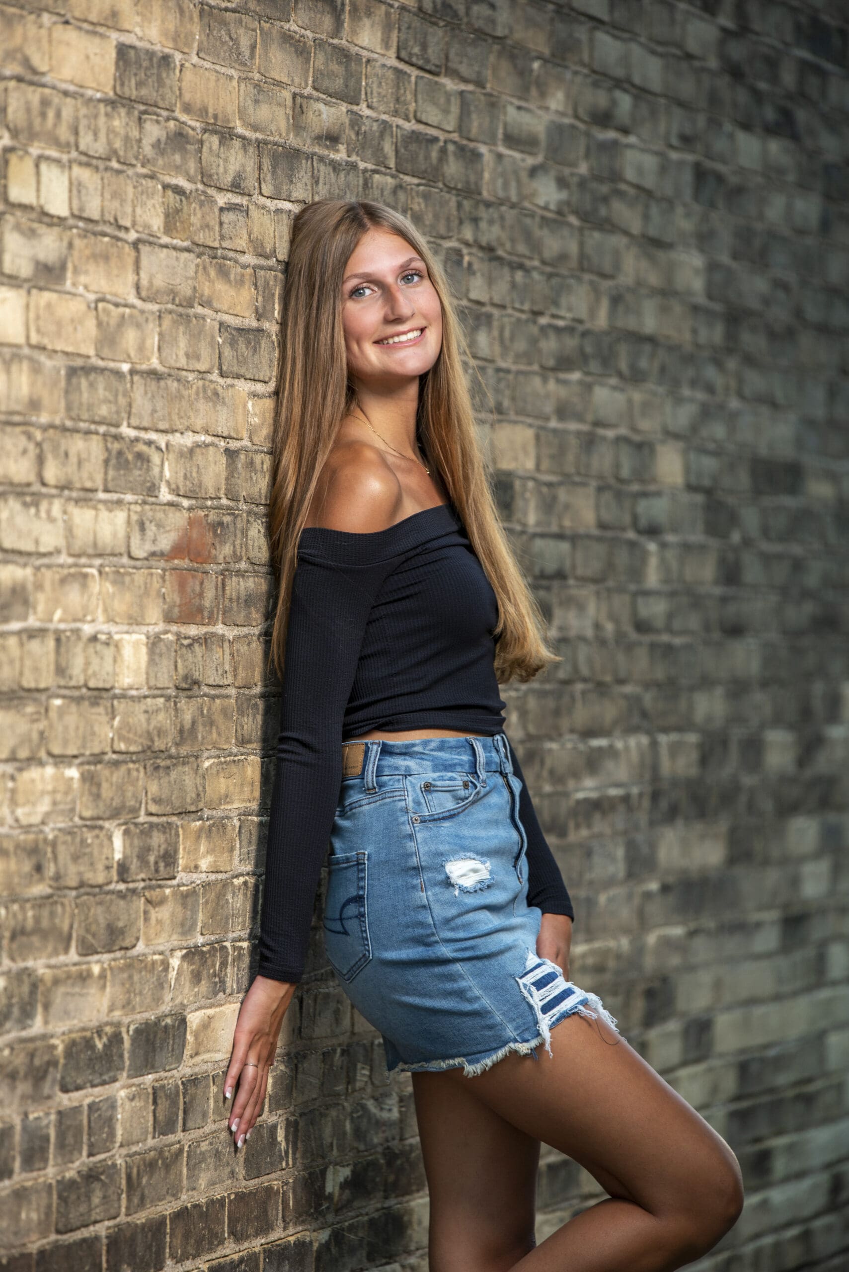Oconomowoc senior standing against wall in downtown. 