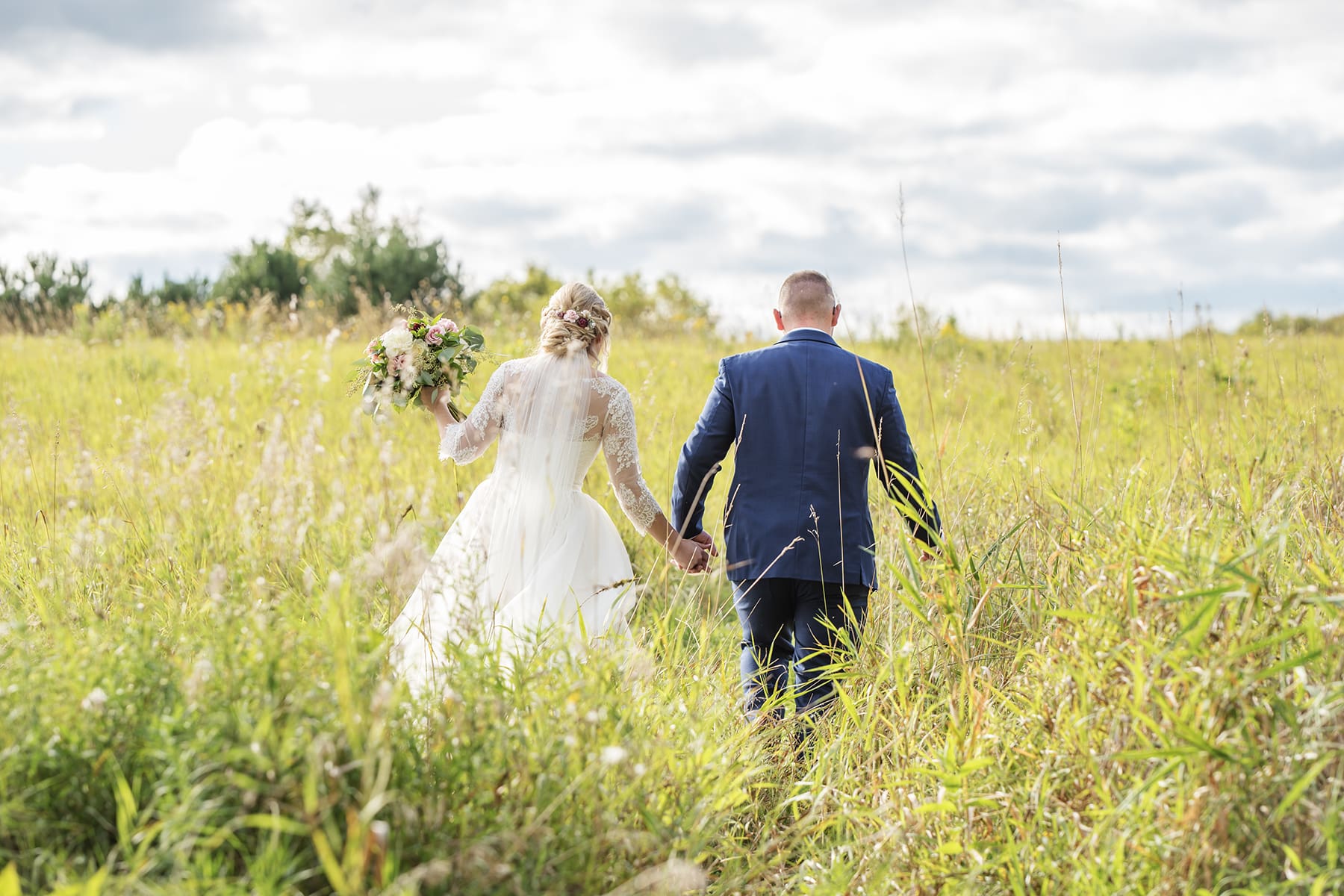 Oconomowoc bride and groom walking through field 