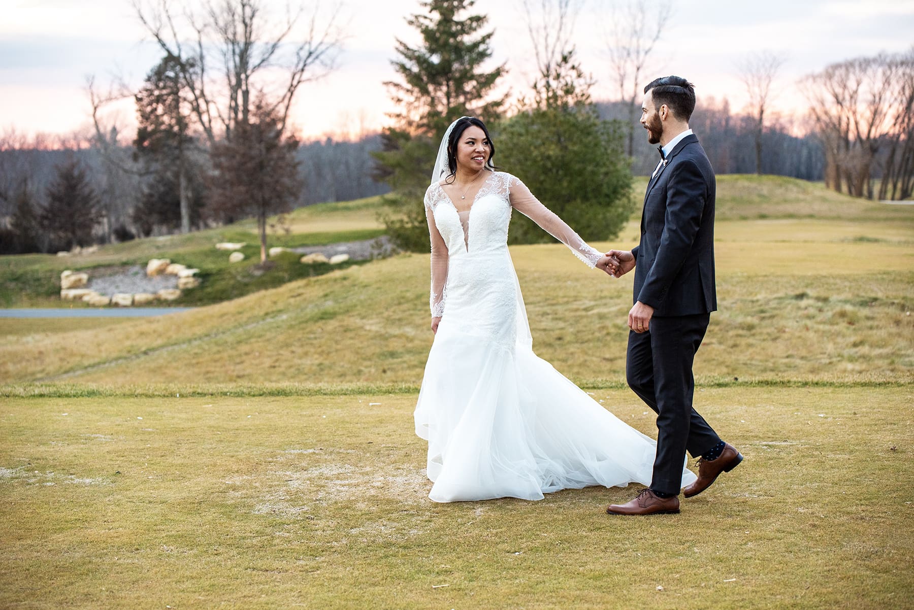 Bride and groom walking on manicured grounds at The Club at Lac La Belle wedding venue