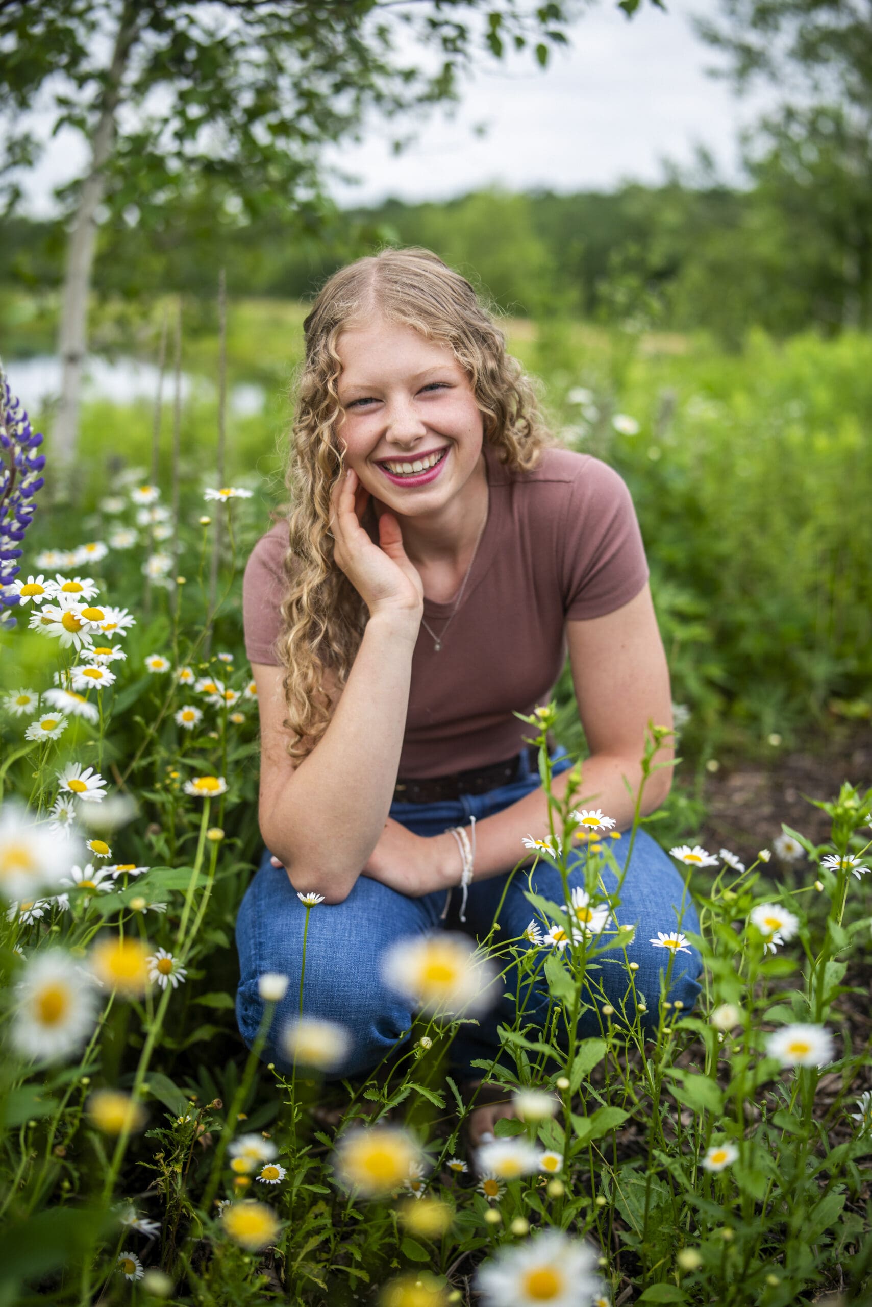 Oconomowoc high school girl laughing in flowers.