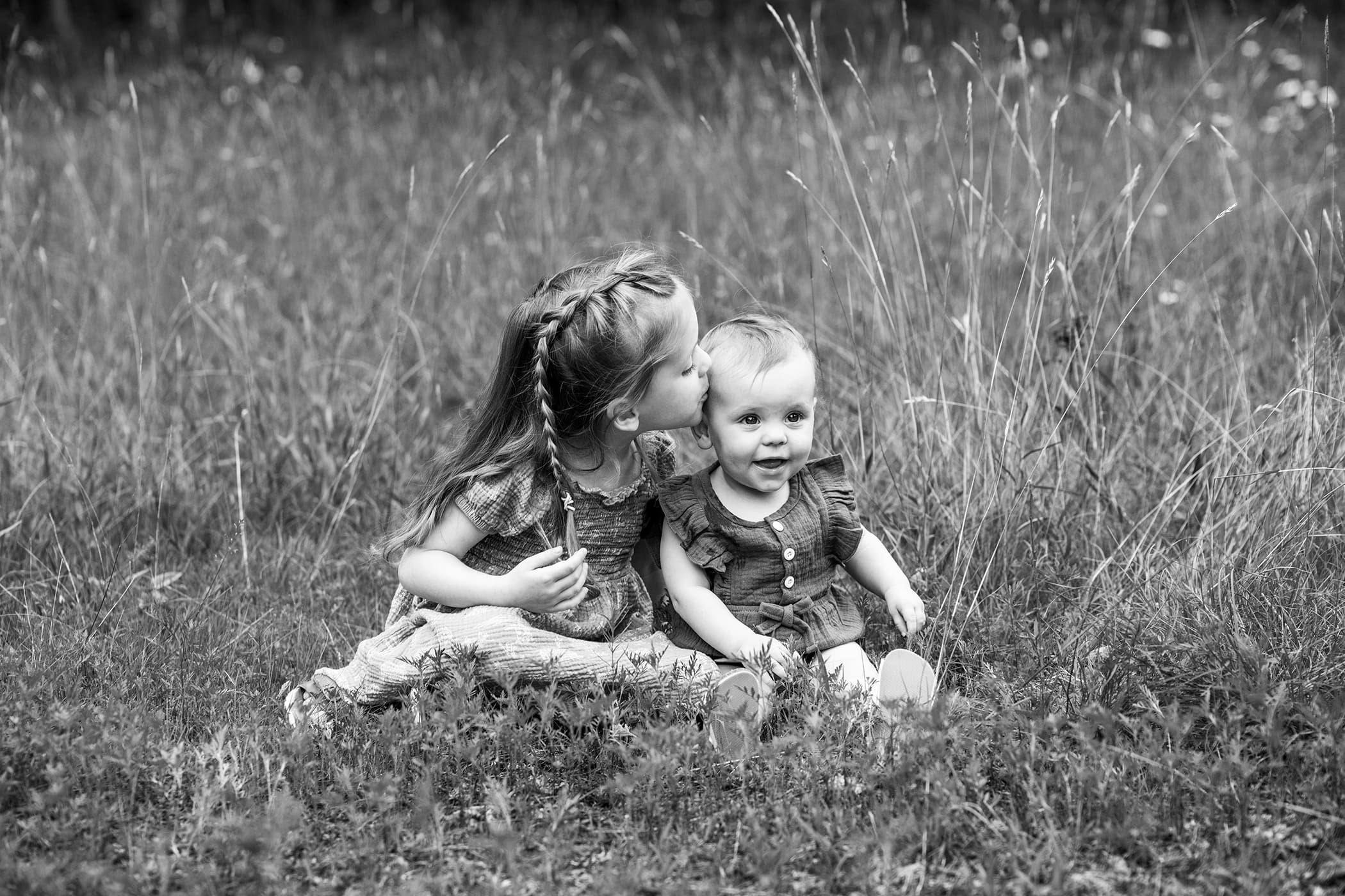 Behind-the-scenes family photography FAQ photo session in Wisconsin as sister kissing her sibling. 