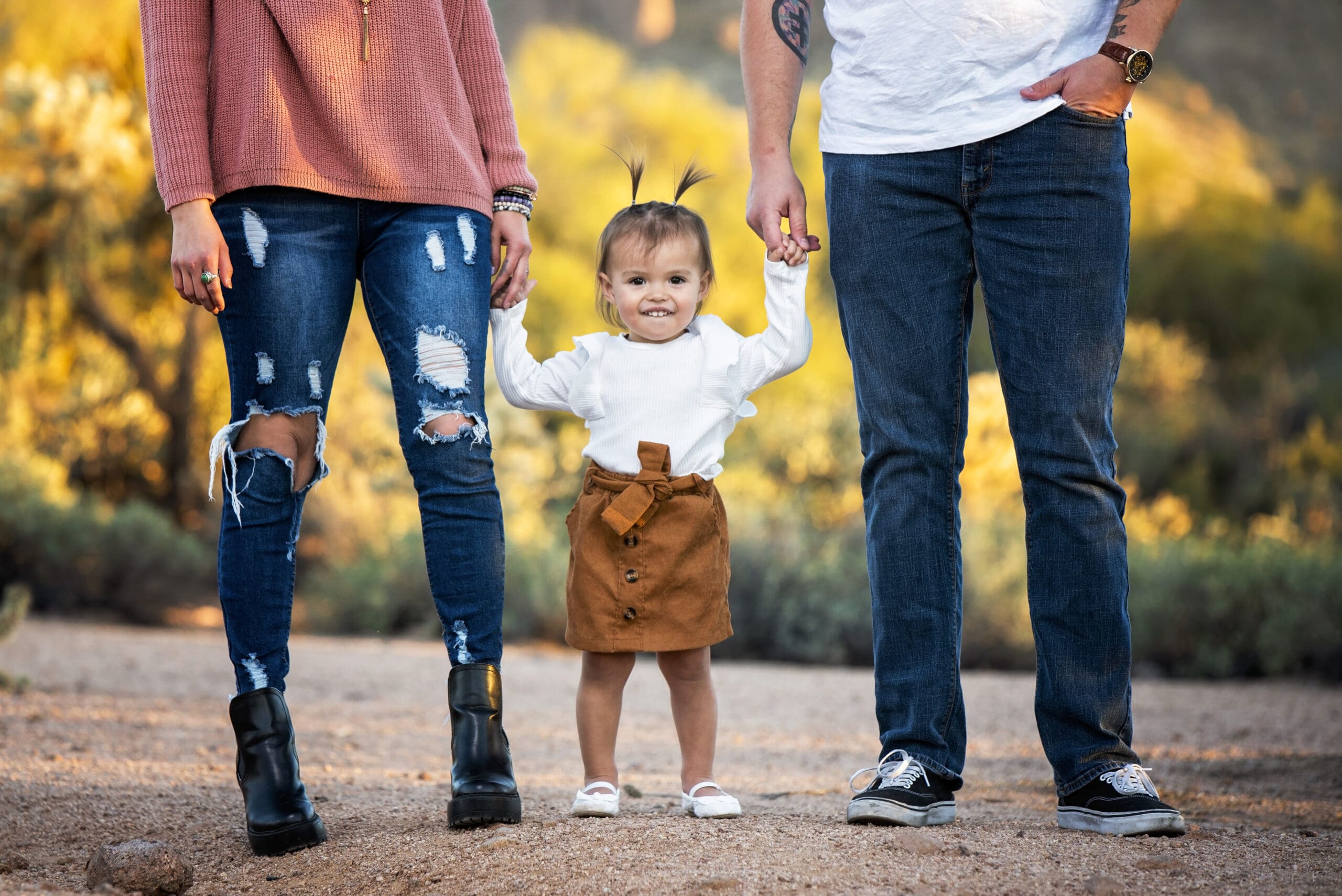 Toddler holding her parents’ hands during an outdoor session, illustrating Wisconsin family photography tips.