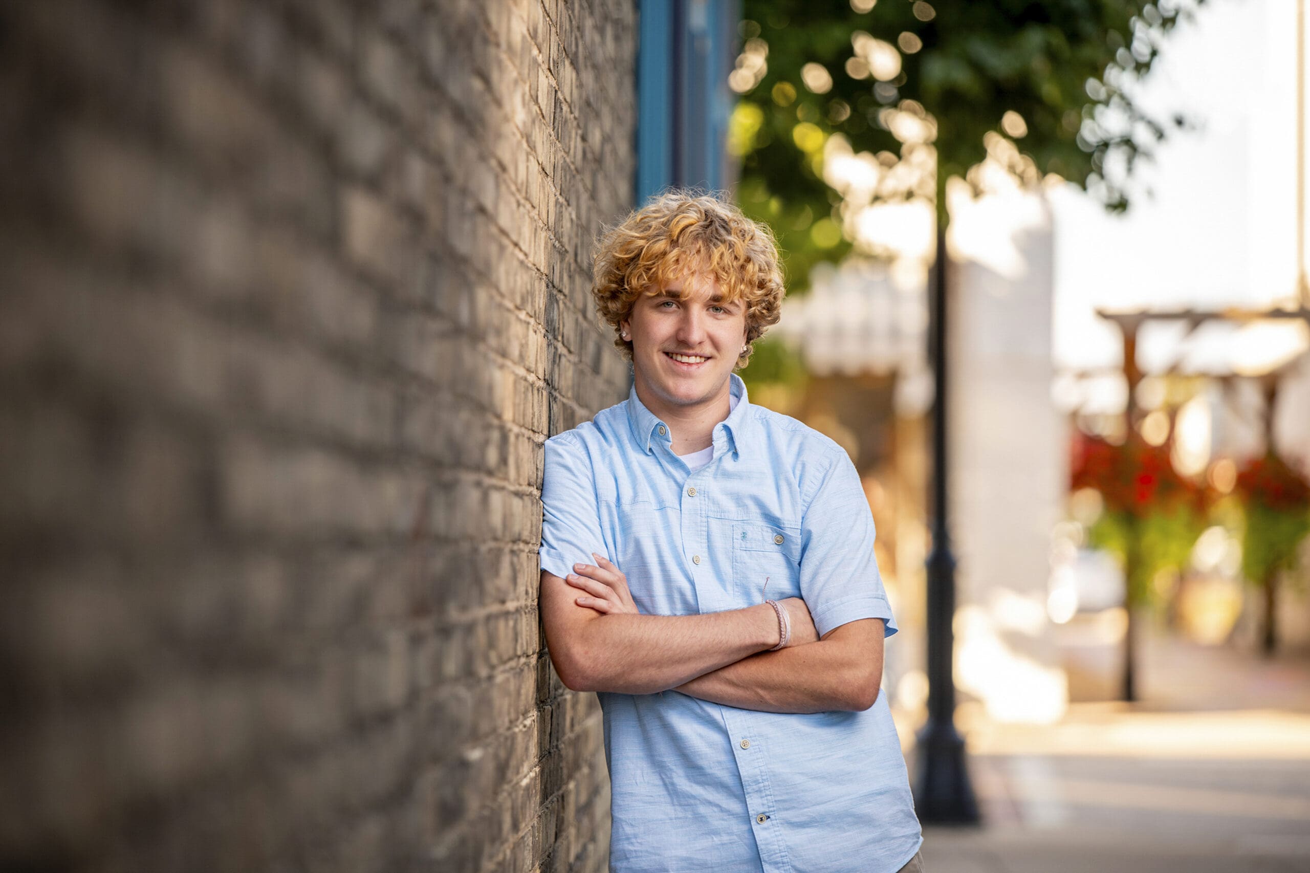 Waukesha County senior leaning against wall downtown.