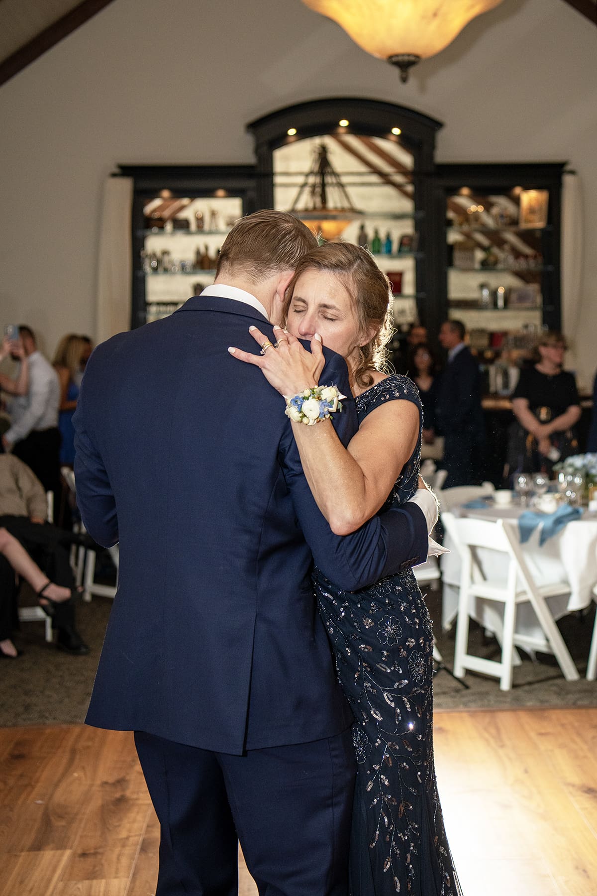 Mother embracing her son while dancing during WI wedding reception 