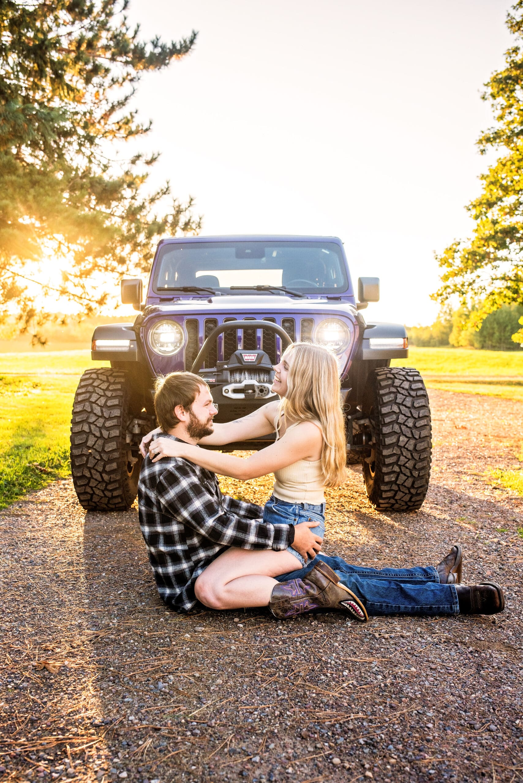Wisconsin engaged couple sitting and laughing in front of their jeep